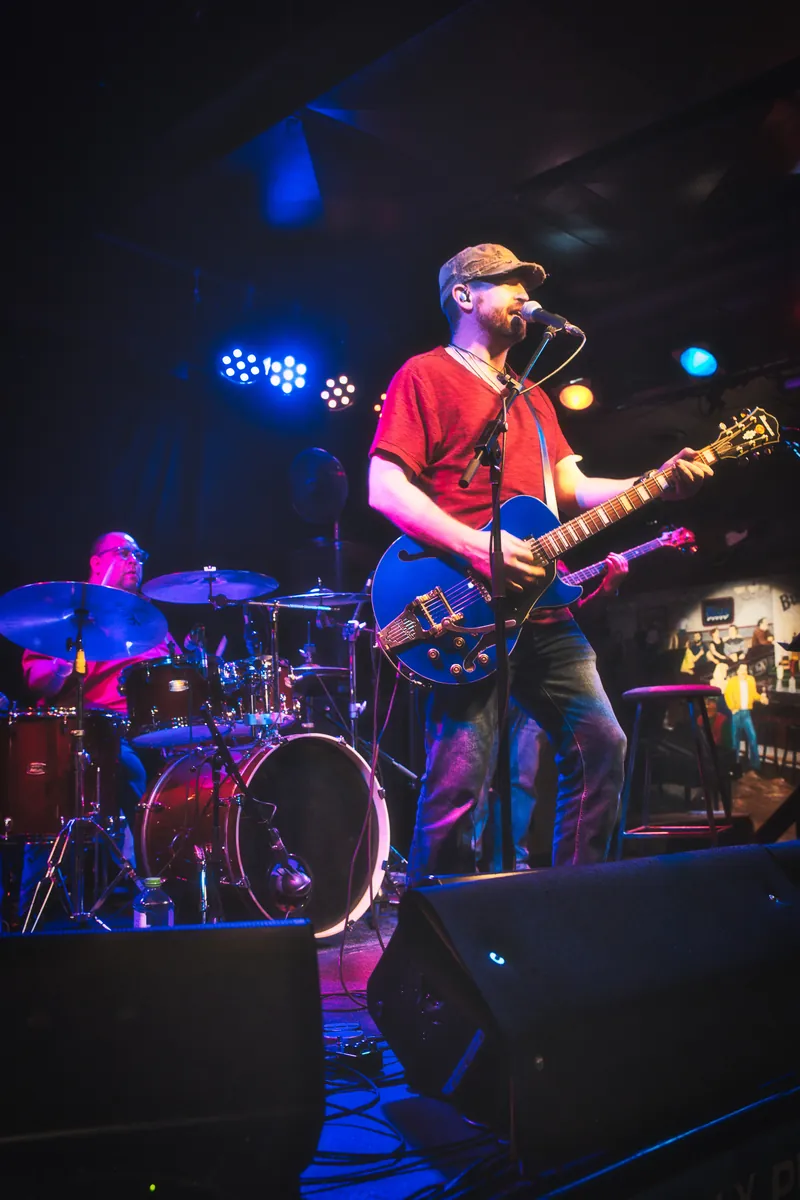 Michael Lander: Live on stage in a red shirt with blue electric guitar